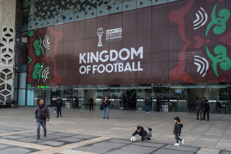 Children play outside a train station with a banner welcoming fans ahead of the Africa Cup of Nations soccer competition, in Rabat, Morocco, Friday, Dec. 19, 2025.